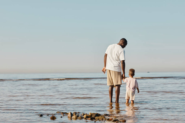 Отец и сын стоят в воде - Фото, изображение