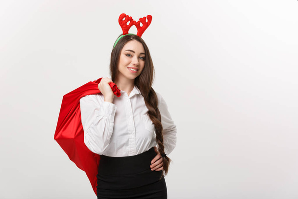 クリスマスのコンセプト-クリスマスのテーマの若い美しいビジネス女性がサンタの赤いバッグを保持. - 写真・画像