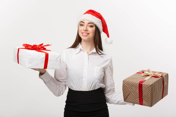 クリスマス コンセプト - 若い幸せな白人ビジネスの女性サンタ帽子側にコピー スペースとギフト ボックスを選択すると. - 写真・画像