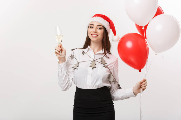 Weihnachtsfeier - Junge schöne Geschäftsfrau feiert Weihnachten mit Glas Champagner und Konfetti Hintergrund. - Foto, Bild
