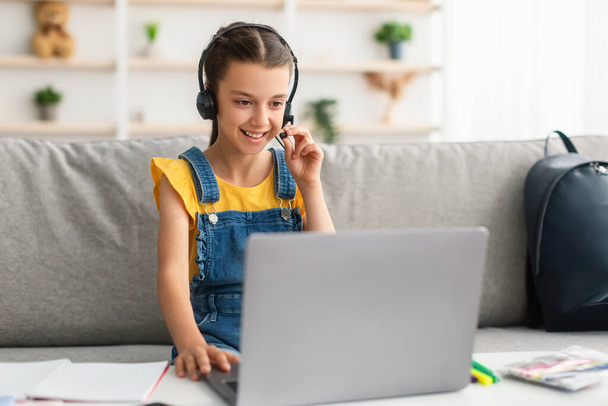 Girl sitting at desk, wearing headphones playing game - Фото, зображення