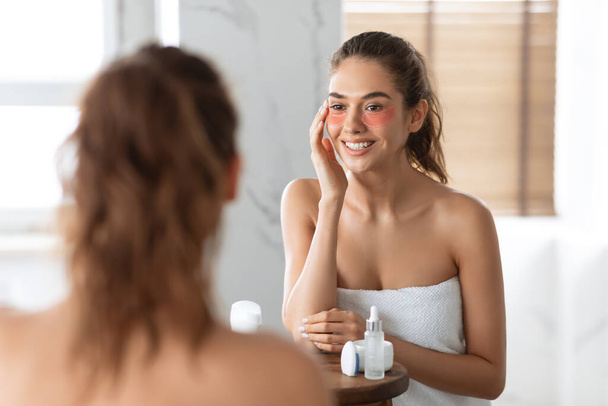 Woman Applying Patches Under Eyes Caring For Skin In Bathroom - Photo, Image