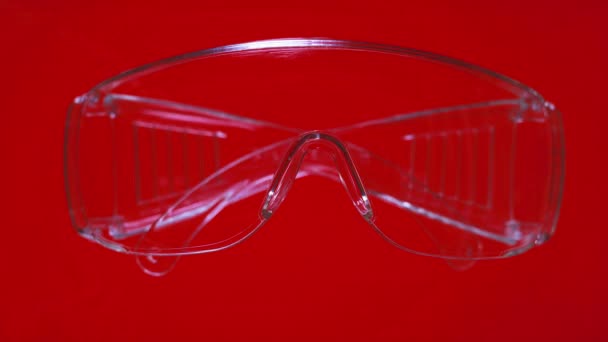 動画を停止鮮やかな赤と緑の背景に保護メガネ。医療と安全の概念。プラスチック製の安全ガラス。個人用保護具。プラスチックゴーグル、職場での透明ガラスの安全性 - 映像、動画