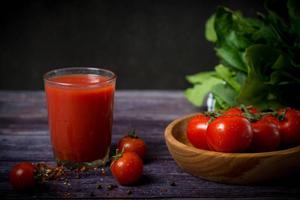 tomates cherry y jugo de tomate sobre un fondo negro. Cóctel de tomate con tomates - Foto, imagen