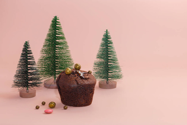 Chocolade muffins, zelfgemaakte taarten. Kerstmis en Nieuwjaar concept. Groene kerstbomen op een roze zachte achtergrond. Kopieerruimte - Foto, afbeelding