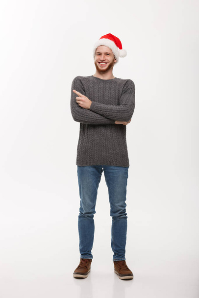 Holiday Concept - Young beard man in sweater enjoy playing and pointing finger onside with copyspace. - Фото, зображення