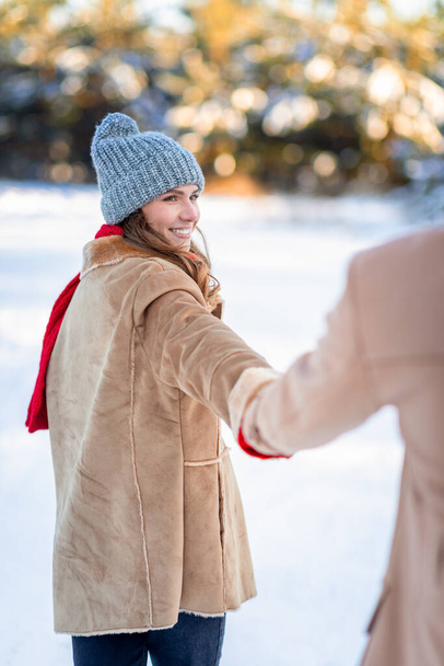 Hymyilevä nuori kaunis nainen vetää mies käsi, nauttia lumesta yhdessä - Valokuva, kuva