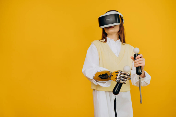 Senhora com braço biônico óculos de realidade virtual e joysticks - Foto, Imagem