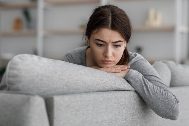 indiferente chateado frustrado europeu jovem feminino senta-se no sofá olhando para vazio em casa - Foto, Imagem
