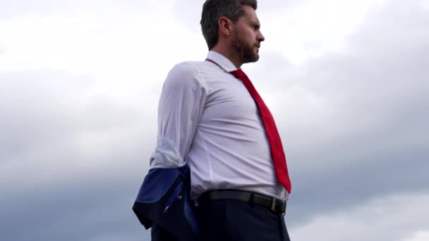 Selbstbewusster bärtiger Chef zieht Jacke auf Himmelshintergrund aus, Büromode - Filmmaterial, Video