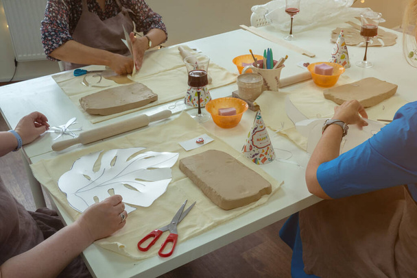 Woman hand potter making clay monstera leaf in pottery workshop studio. Process of creating ceramic vase. Handmade, hobby art and handicraft concept - Fotó, kép