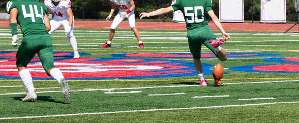 Un joueur de football du lycée donne un coup de pied au ballon pendant le coup d'envoi d'un jeu pendant un match. - Photo, image
