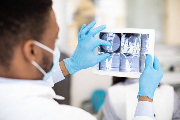 African American Male Dentist Doctor Using Digital Tablet, Checking Patients Teeth Xray - Fotó, kép