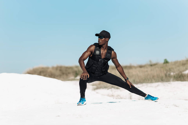sporty African American man, in sportswear, doing stretching in the early morning outdoors, Amazing mountain view in the background - Фото, изображение