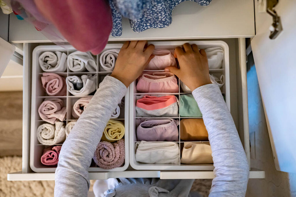 Female hands organizing storage of underwear socks t shirts use Marie Kondos method. Perfectionist Teenage girl - Foto, Imagem