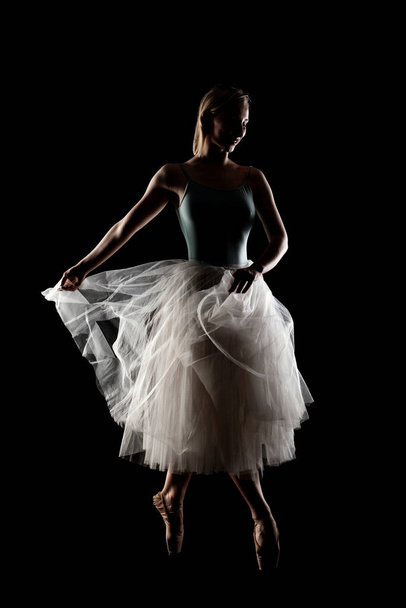 ballerina with a white dress and black top posing on black background - Zdjęcie, obraz