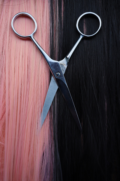 Stříhání vlasů nůžky na černé a růžové vlasy pozadí - Fotografie, Obrázek