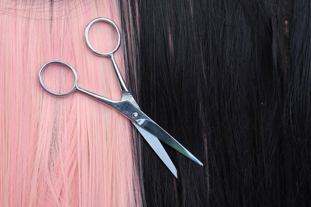 Haarknipschaar op zwart en roze haar achtergrond - Foto, afbeelding
