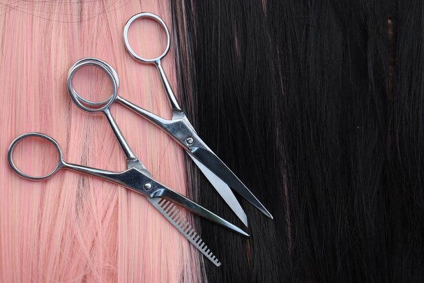 Tijeras de corte de cabello sobre fondo de pelo negro y rosa - Foto, imagen