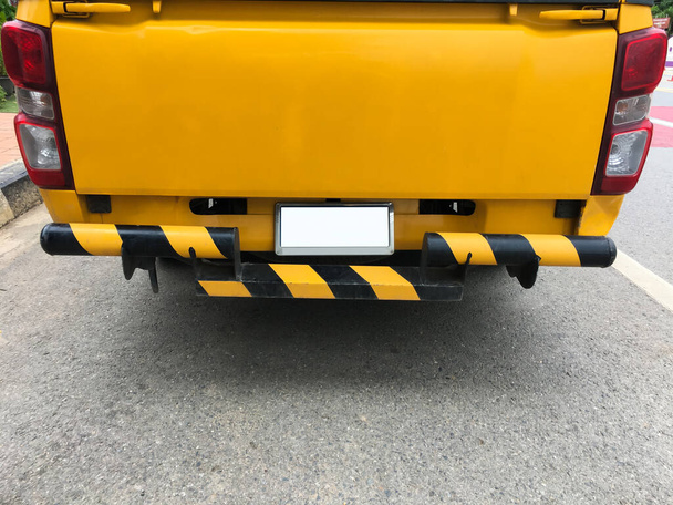 Os oficiais de headbands pretos e amarelos feitos na parte traseira do caminhão de coleta amarelo para simbolizar veículos de manutenção de rodovias. Foco suave e seletivo. - Foto, Imagem