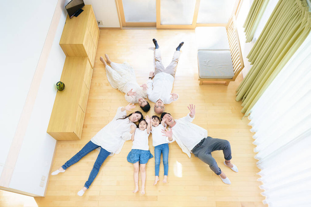 3 generation family lying on the floor in the room - Фото, изображение