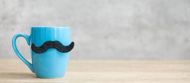 Blue coffee cup or tea mug with Black mustache decor on table. Blank copy space for text. Blue November, Happy Father day and International men day concept - Photo, Image