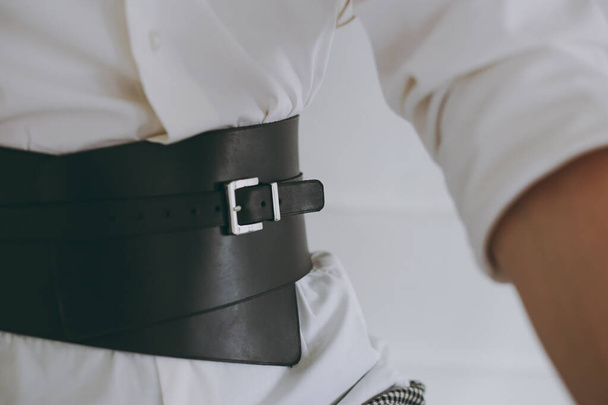 Chica joven en una camisa de oficina blanca probándose un cinturón de cuero - Foto, imagen