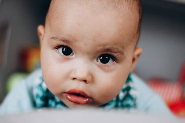 Милый маленький мальчик с пухлыми щеками и большими глазами. Портрет счастливого младенца - Фото, изображение