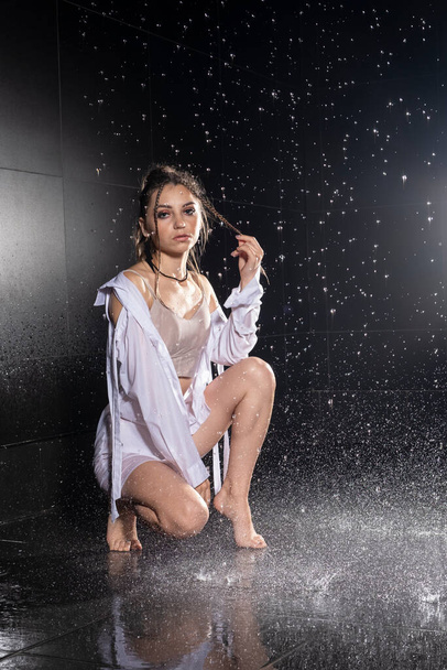 Girl in wet clothes posing under streams of water - Foto, Imagem