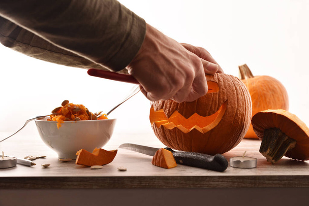 Detail of man carving and emptying a pumpkin for the halloween party. Front view. Horizontal composition. - Foto, imagen