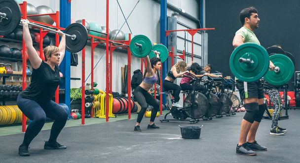 Personas que practican levantamiento de pesas levantando pesas en el gimnasio - Foto, Imagen