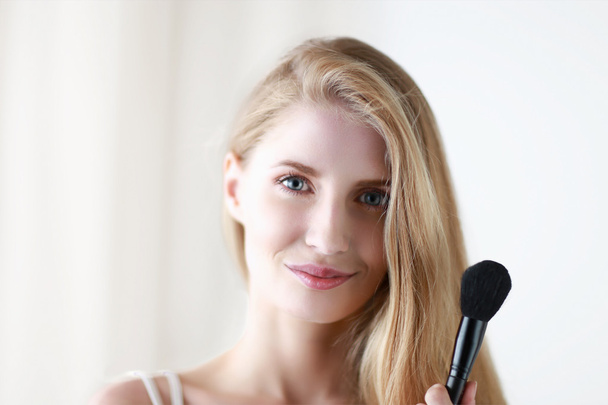 Pretty woman applying make up with brush - Фото, зображення