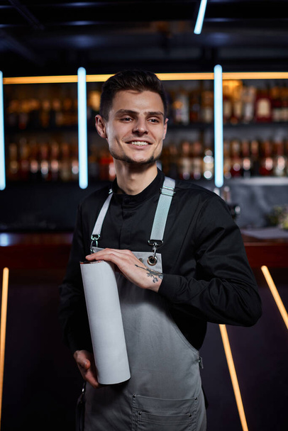 Handsome barman in apron standing at the bar counter - Photo, Image