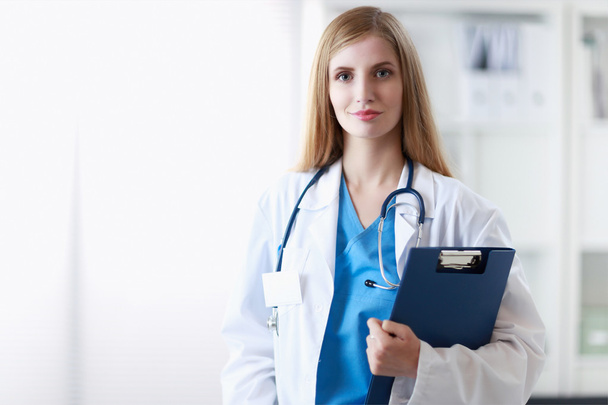 Portrait of woman doctor with folder at hospital corridor - Zdjęcie, obraz