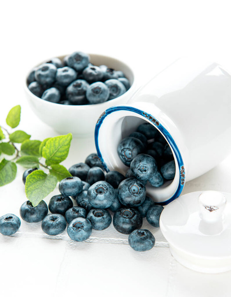 Freshly picked blueberries on a white tile background. Concept for healthy eating - Photo, Image