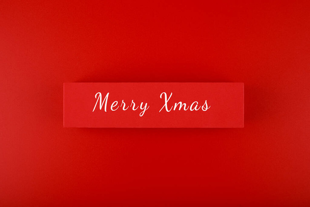 Minimal elegant flat lay Christmas theme. Merry Christmas text hand written on red tablet on red background. Creative layout in red colors - Fotoğraf, Görsel