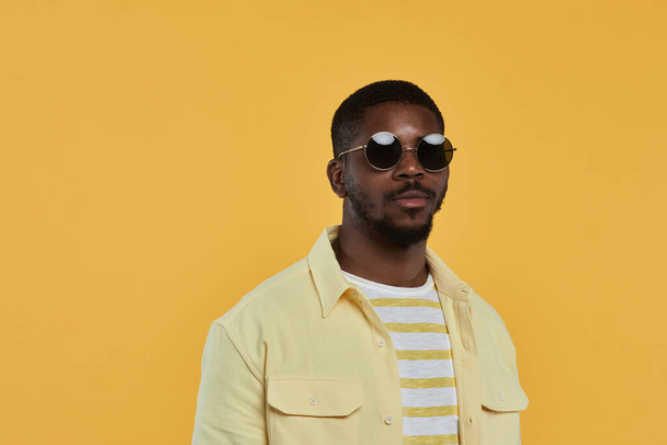 Hombre afroamericano guapo usando gafas de sol en amarillo - Foto, Imagen