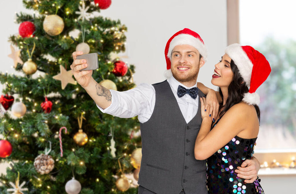 couple in santa hats taking selfie on christmas - Valokuva, kuva