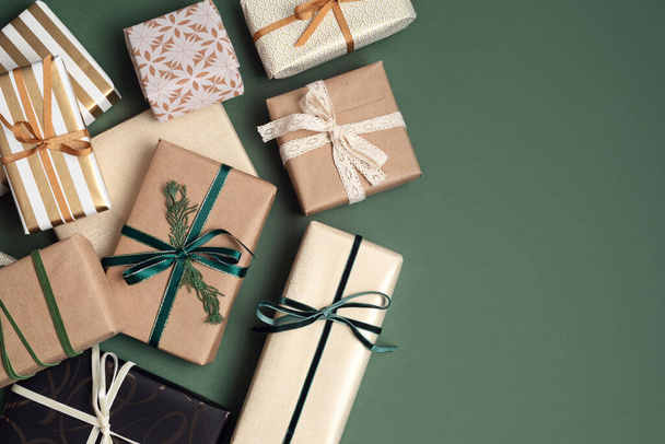 Yeşil zemin üzerinde hediye kutularıyla Noel arkaplanı. Xmas kutlaması, kış tatili hazırlıkları, gizli Noel Baba, takvim konsepti. Şenlikli maket, üst görünüm, düz yatış - Fotoğraf, Görsel