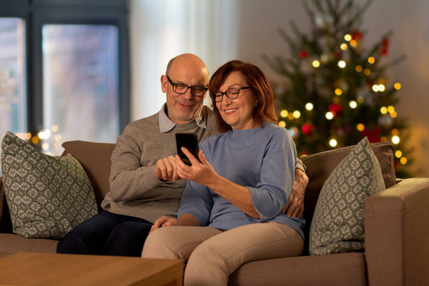 senior couple with phone at home on christmas - 写真・画像