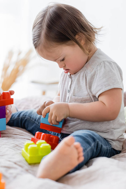 Toddler girl with down syndrome playing building blocks near parent at home  - Fotografie, Obrázek