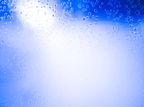 Primer plano, gotas de agua en el cuarto de baño de vidrio esmerilado o ventana, puerta, luz blanca reflejada desde el interior, pared azul, Tailandia. - Foto, Imagen