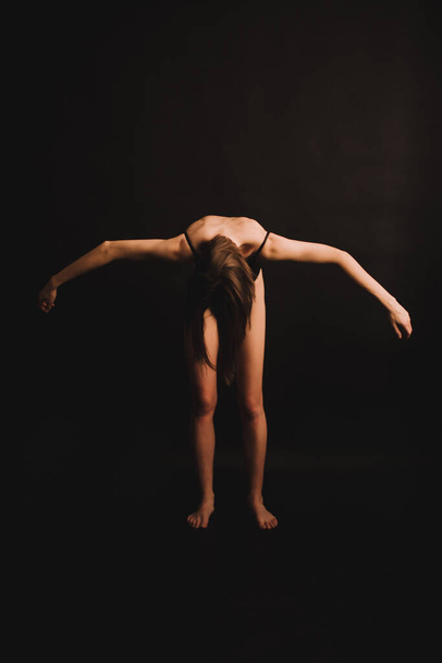abstract poses on the floor, a girl in a classic bodysuit intuitively dancing on a black background, fuzzy photos and blurring, art image noises, unfocused full-length portraits - Photo, image