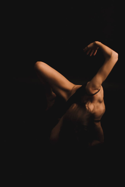 body details, tanned legs on a dark background, unfocused body parts - Fotografie, Obrázek