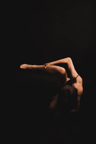 body details, tanned legs on a dark background, unfocused body parts - Foto, Bild