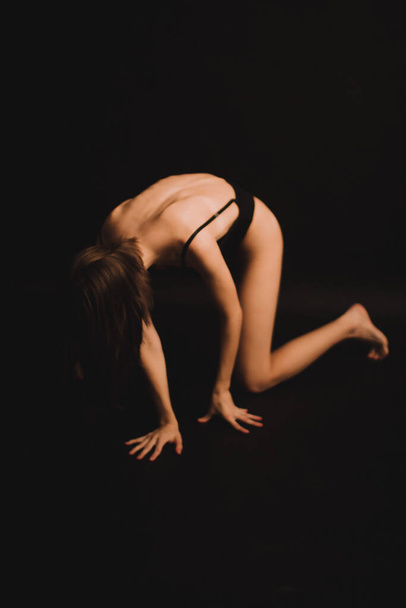 body details, tanned legs on a dark background, unfocused body parts - Foto, afbeelding