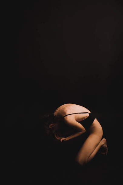 abstract poses on the floor, a girl in a classic bodysuit intuitively dancing on a black background, fuzzy photos and blurring, art image noises, unfocused full-length portraits - Φωτογραφία, εικόνα