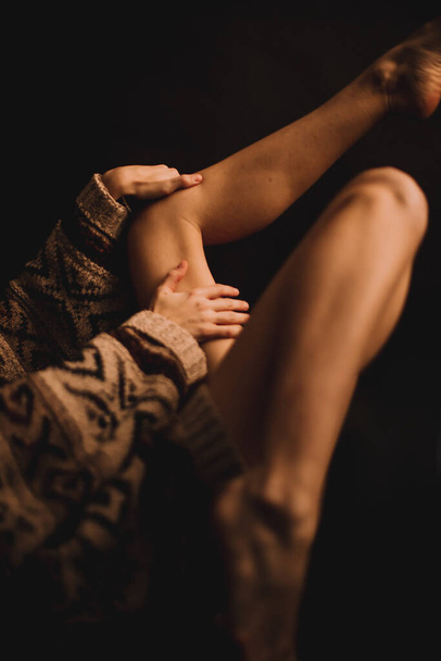 body details, tanned legs on a dark background, unfocused body parts - Фото, изображение