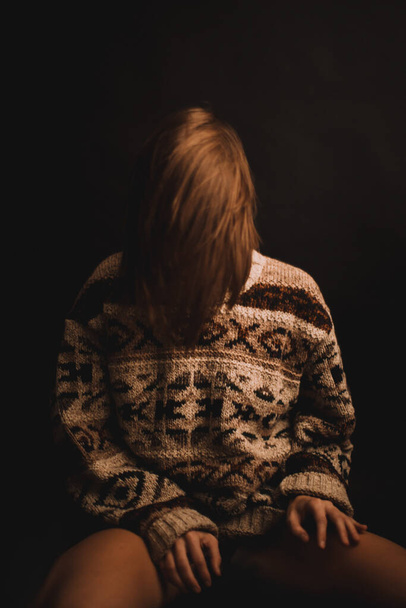 girl in an old grandfather's sweater with a hippie ornament on a dark background, fuzzy and blurred portraits, blurred film and fine grain - Photo, image