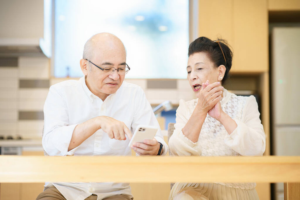Seniorenpaar nutzt Smartphone durch Versuch und Irrtum im Zimmer - Foto, Bild
